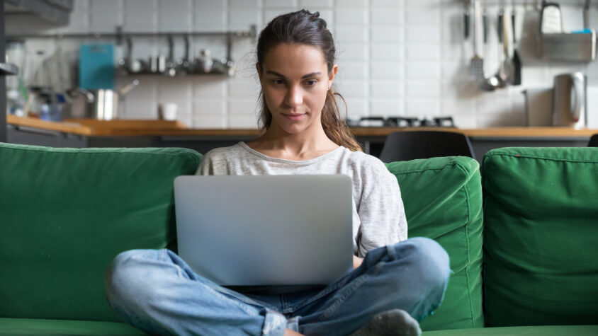 A woman sitting on a couch using a laptop