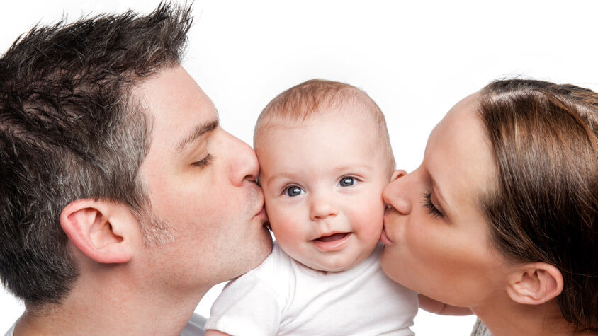 A man and a woman kissing a baby
