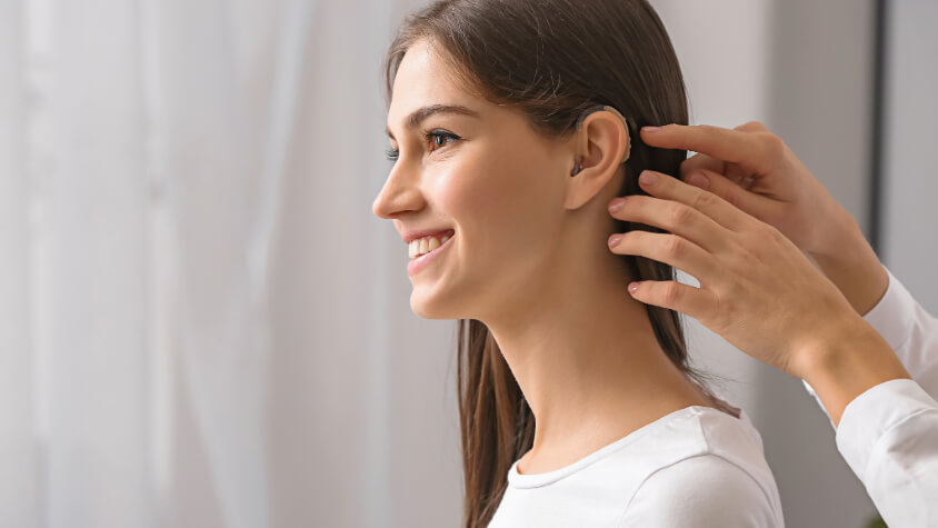 A hearing aid is fitted to a woman's ear