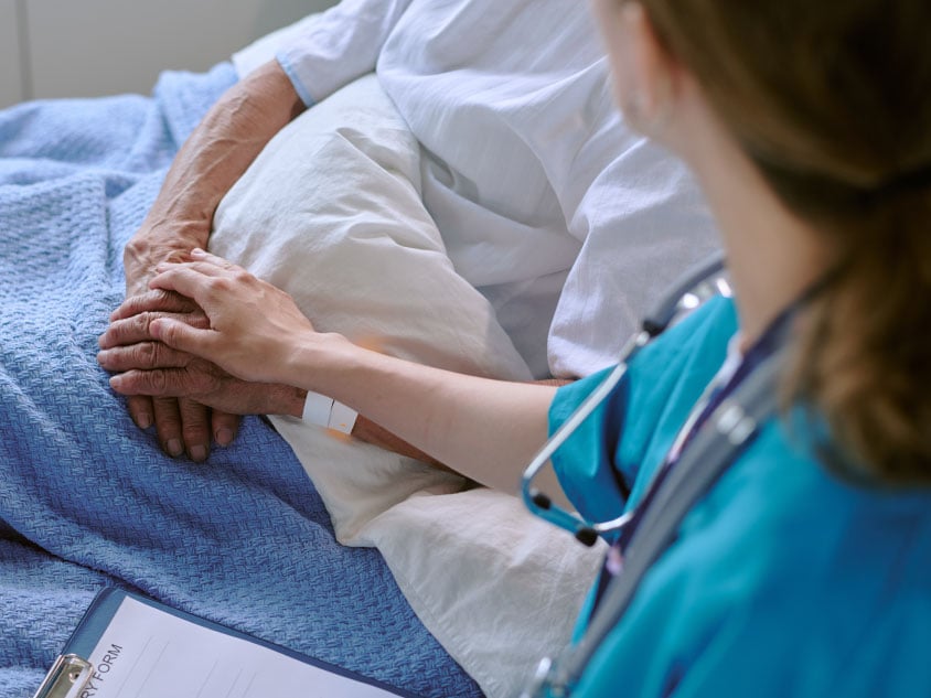 A nurse holding a patient's hand