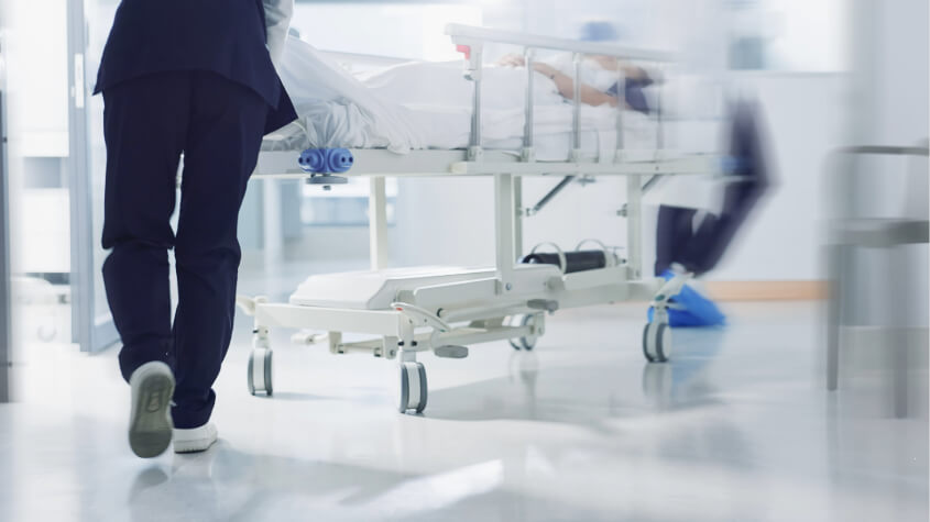 Hospital staff pushing a hospital bed