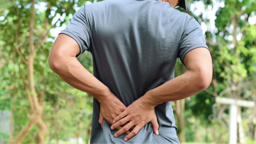 A man puts his hand on his back